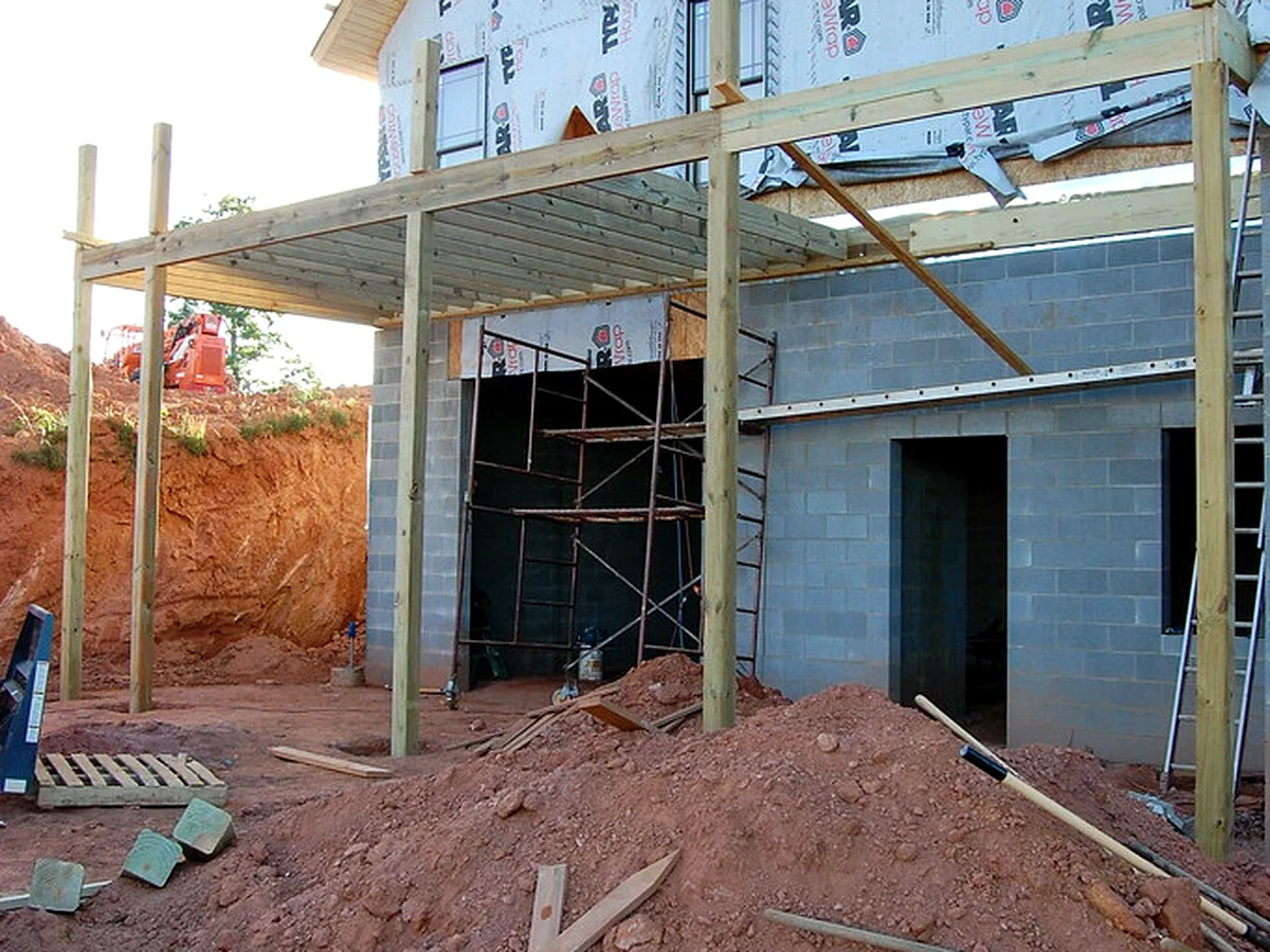 Close-up of a deck ledger board bolted to house siding with flashing along the top edge
